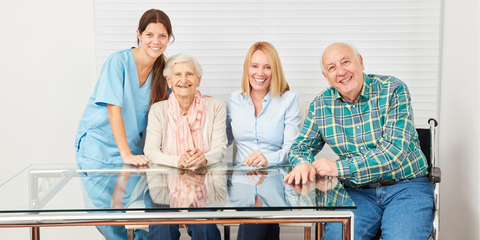 Smiling caregiver with two happy seniors and a family member, depicting elder care and support.